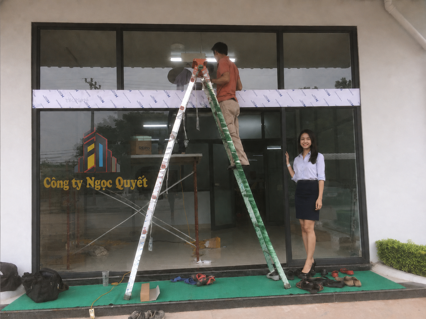 Nhân viên thi công lắp Cửa  kính mặt tiền Công ty Ngọc Quyết với nữ nhân viên đứng trước cửa kính